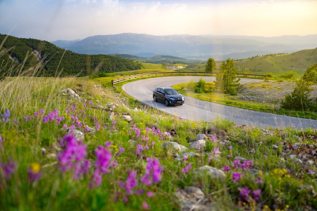 suzuki vitara hybrid 4x4 2024 sur route de montagne vers aigle en suisse dans les alpes suisses partir en vacances en voiture