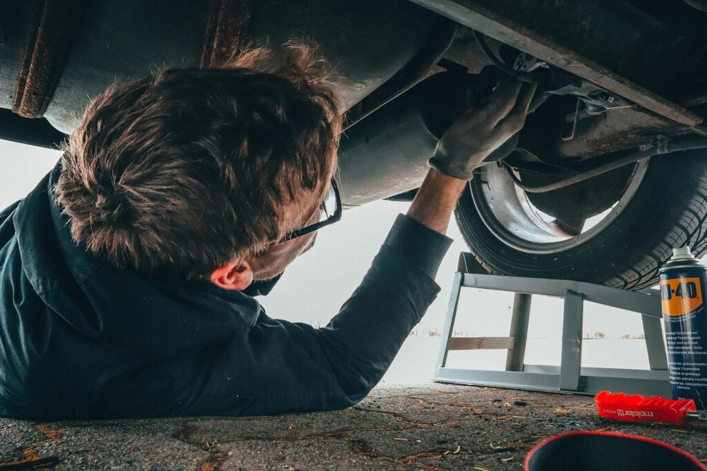 entretien voiture printemps homme répare sa suzuki swift sous la voiture garage aigle suzuki
